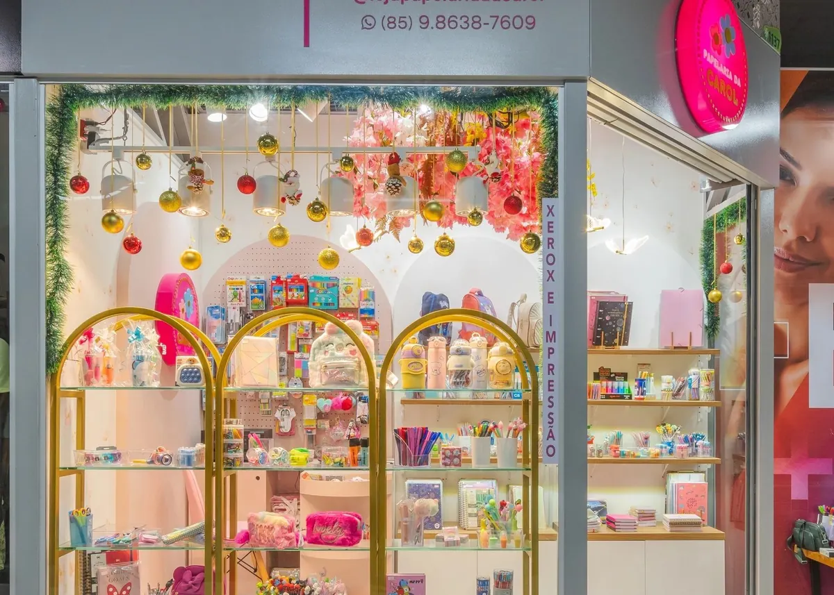 Fachada de loja comercial com vitrine, arcos dourados de exposição e prateleiras de papelaria