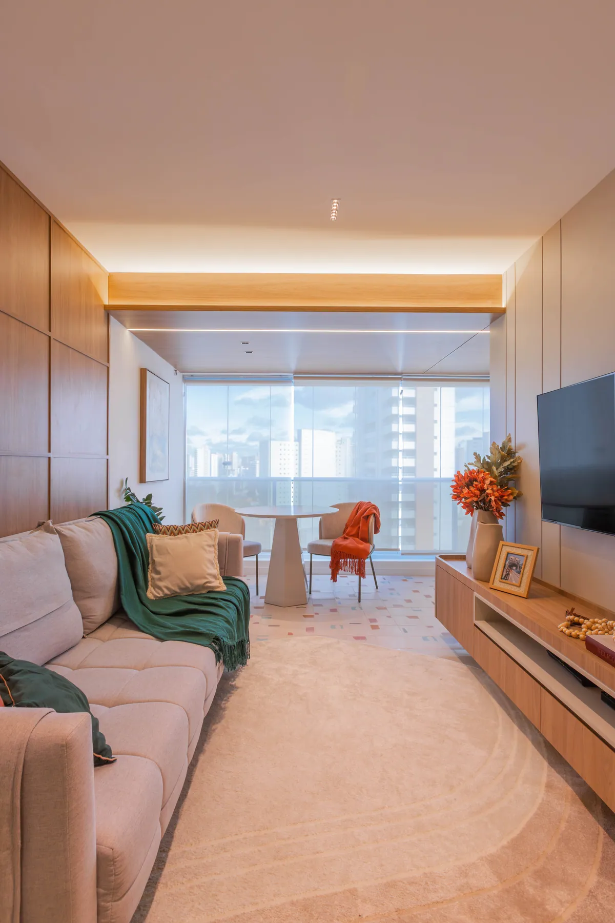 Sala de estar do Apartamento Blue com sofá bege, manta verde e janela de vidro ao fundo