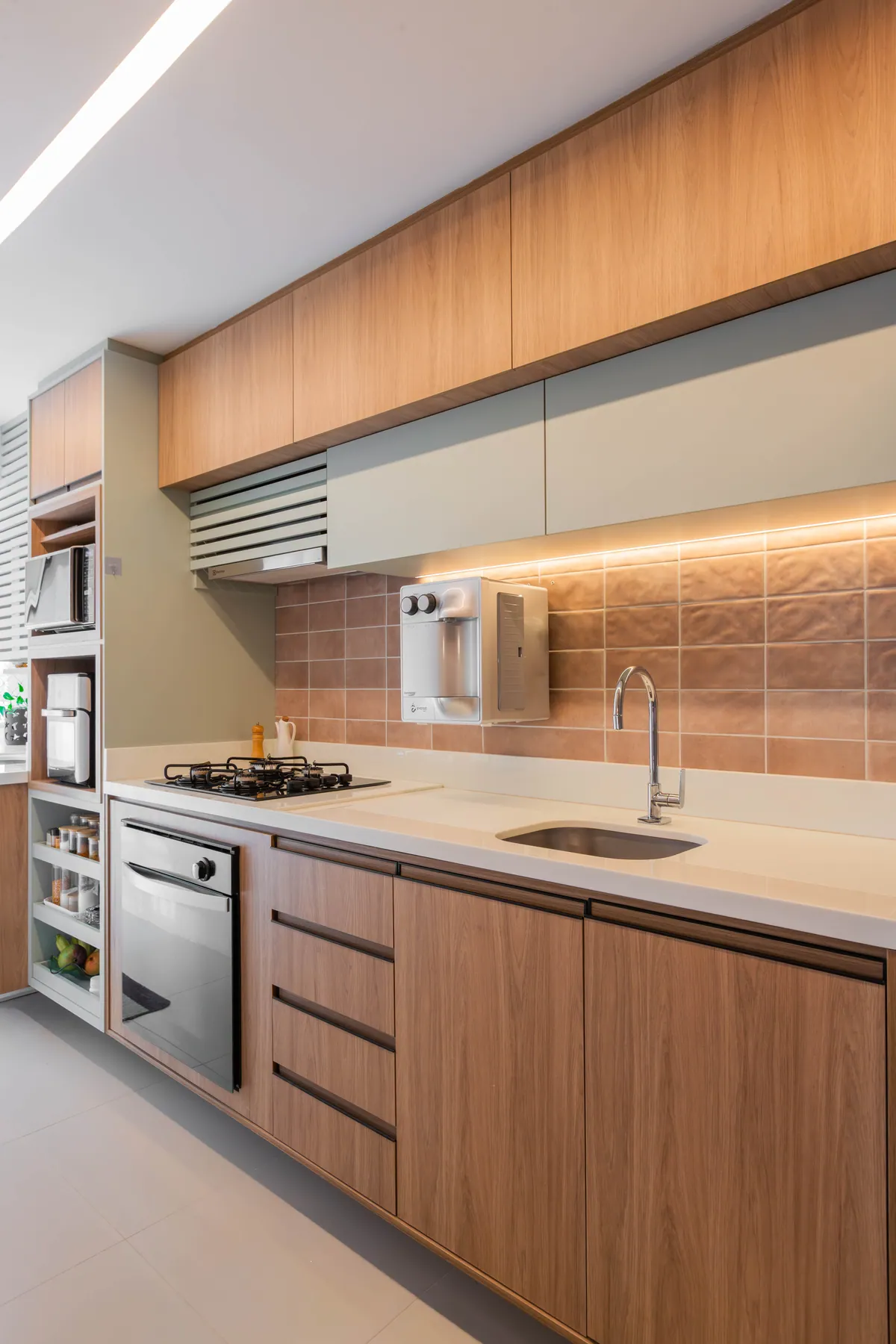 Cozinha do Apartamento Blue com marcenaria em madeira, revestimento terracota e cooktop